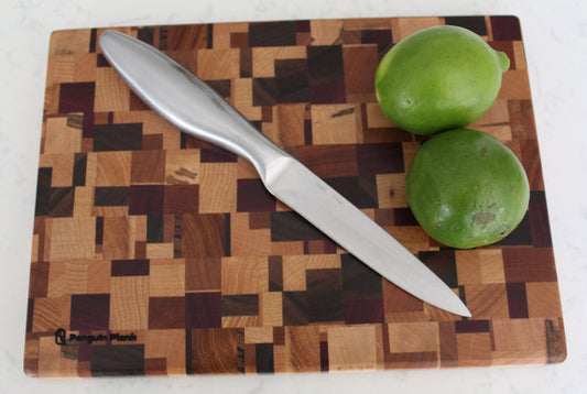 Wooden cutting board with a knife and two limes on a white background