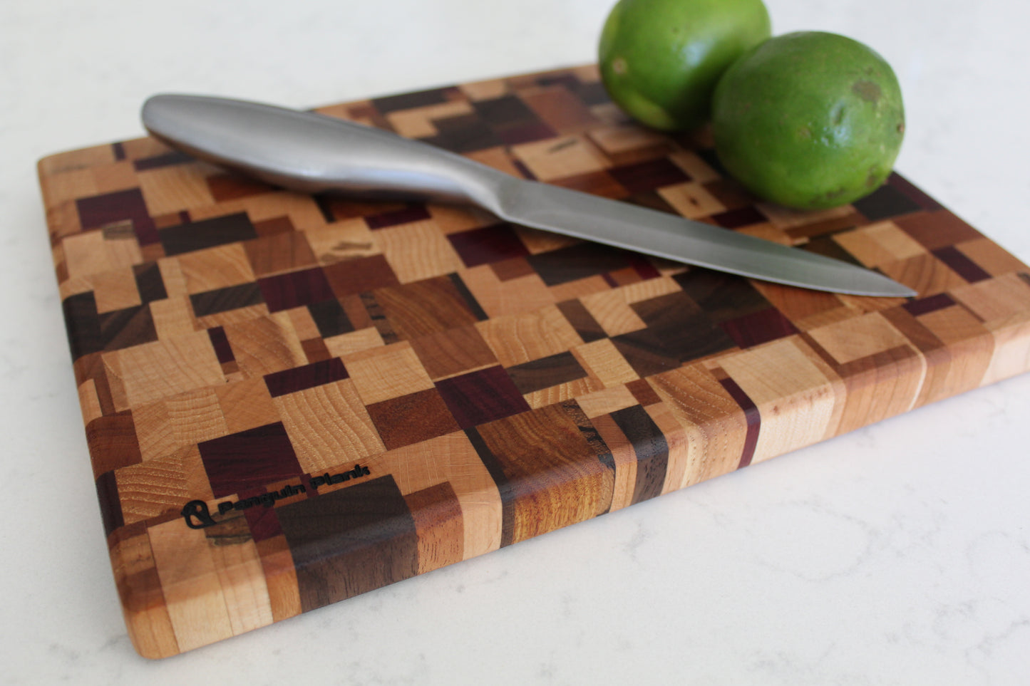 Wooden cutting board with a knife and limes on a white surface