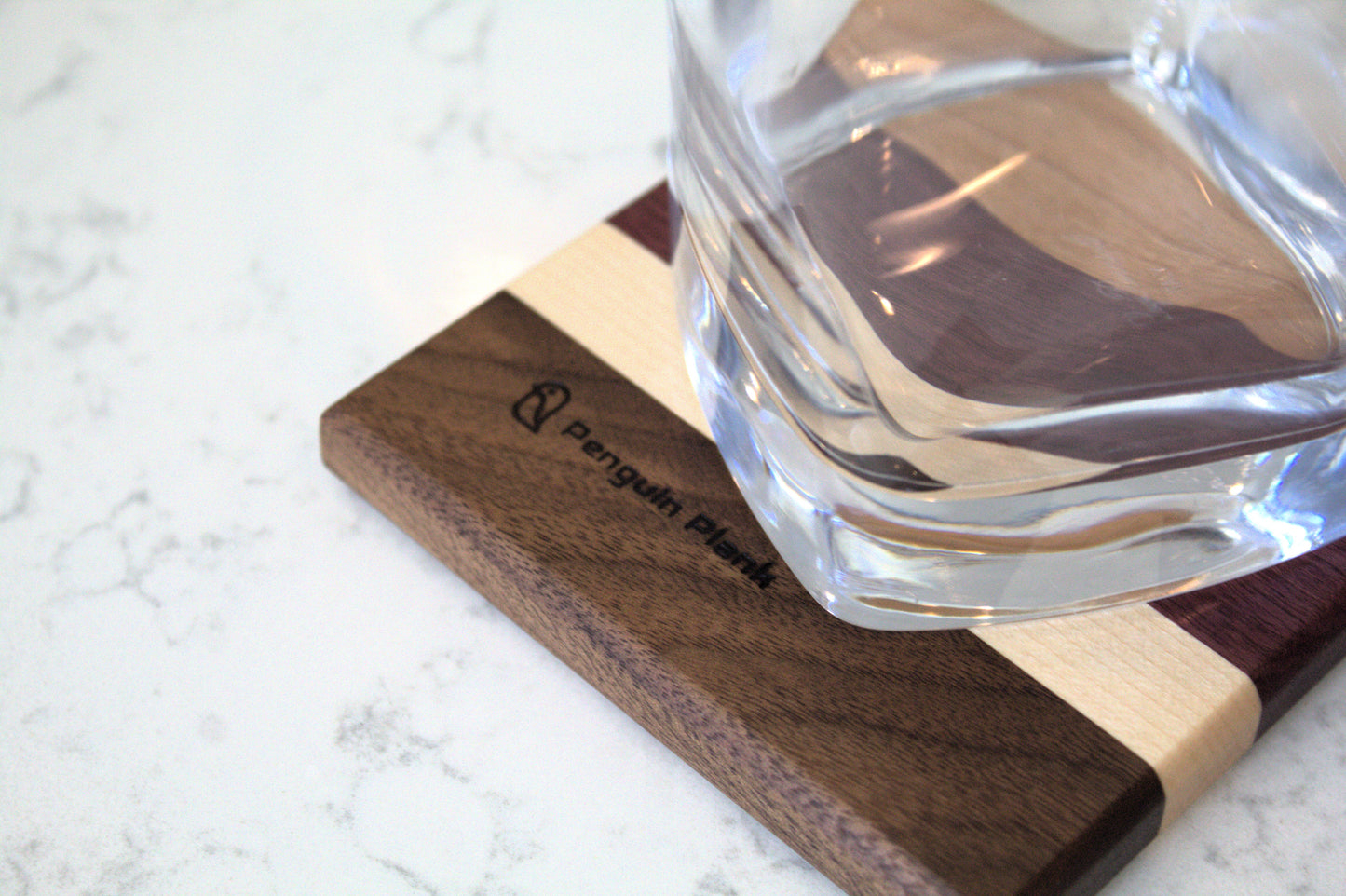 Glass on top of wood drink coaster made from cherry, purpleheart, maple and walnut.