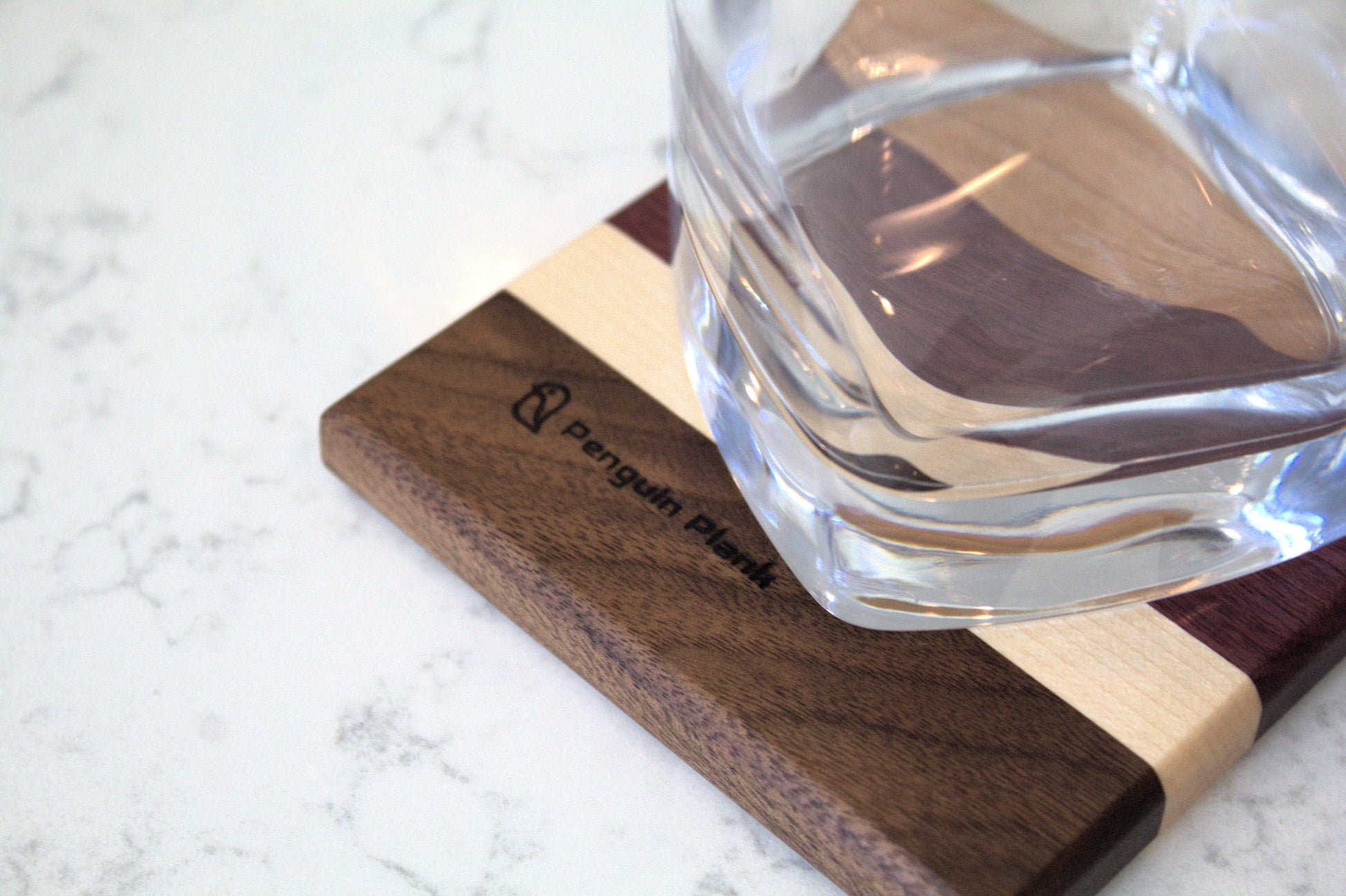 Glass on top of wood drink coaster made from cherry, purpleheart, maple and walnut.
