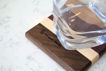 Glass on top of wood drink coaster made from cherry, purpleheart, maple and walnut.