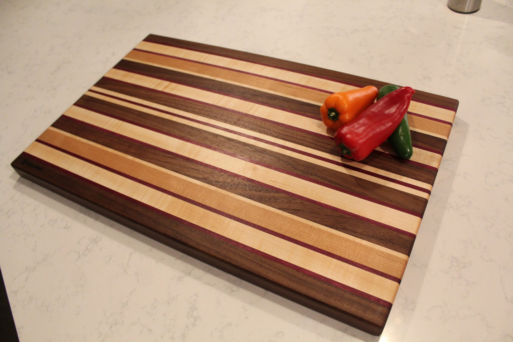 Large Wood Cutting Board, made from a unique blend of Walnut, Maple, Cherry, and Purpleheart strips shown with assortment of peppers.